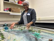 Geosciences graduate student Amina Abdulsalam shows how streams impact the landscape using a stream table feature. Credit: Aagje Eijsink / Penn State. Creative Commons