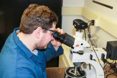 Nathan Gendrue, graduate student in mining and mineral process engineering who is advised by Shimin Liu, reviews the characterization of coal dust under a high-resolution microscope. IMAGE: PENN STATE