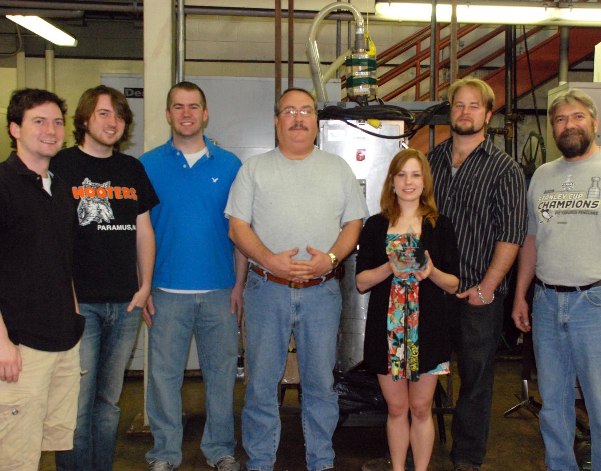 From left to right: Adam Kimmerle, Liam O’Sullivan, Timothy Tomko, Keith Miska, Natalie Keener, Shaun Valentine, and Ronald Wasco stand in front of the team’s design. 