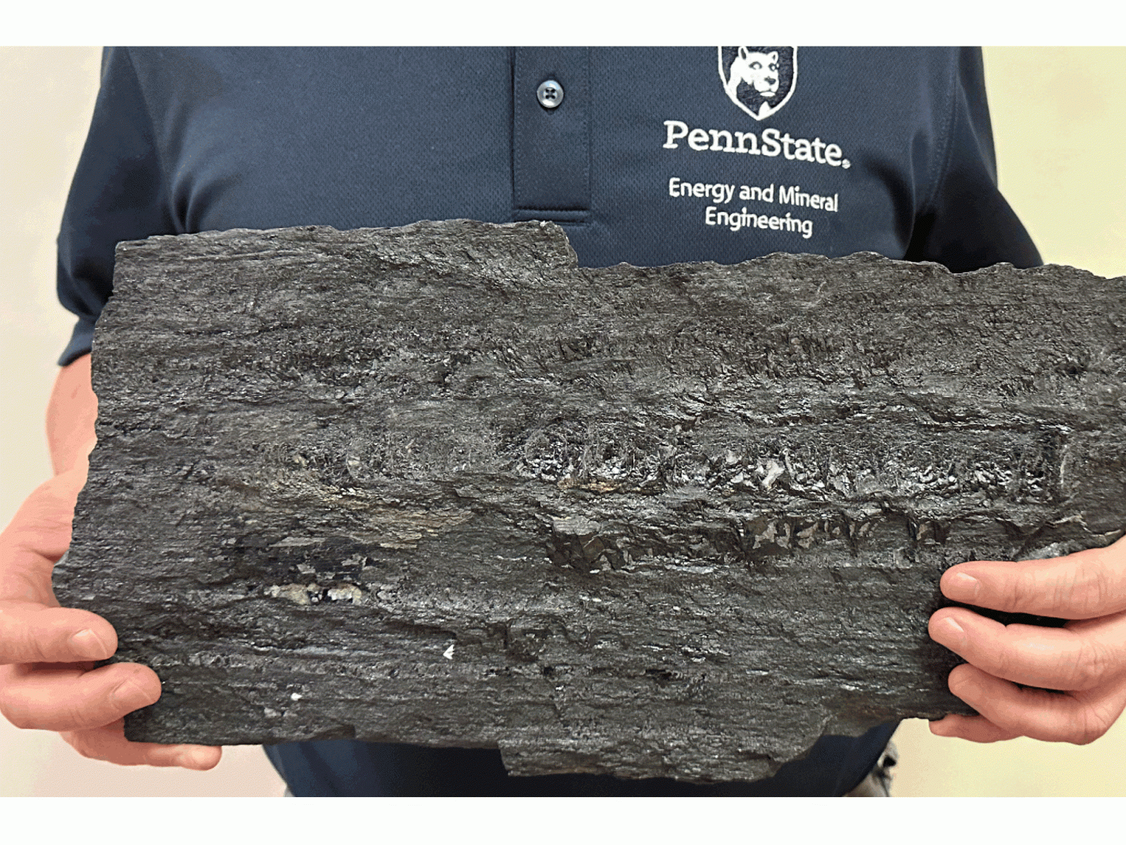 A Penn State researcher holds a large piece of coal.