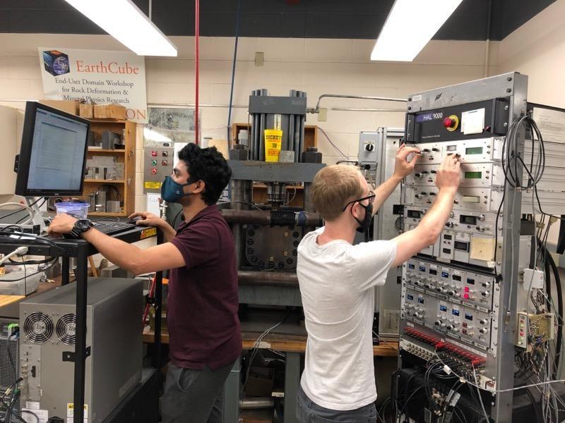 Two grad students a series of tests on fractured rock using acoustic vibrations that simulate seismic activity.